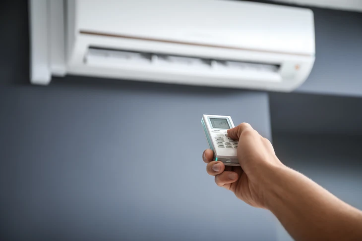 Extérieur résidentiel avec unité extérieure de climatisation installée contre un mur blanc